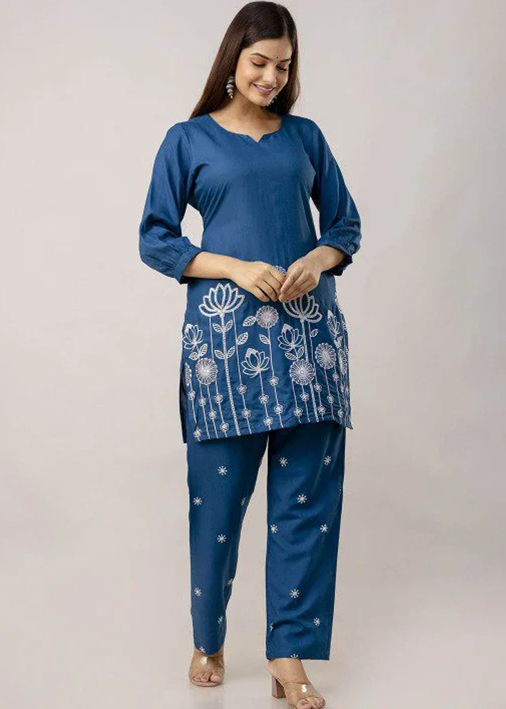 Women’s blue solid straight-fit kurta and pant set in viscose rayon, featuring floral embroidery on the front, a round neckline, three-quarter sleeves, above-knee length, paired with matching embroidered slip-on trousers with an elasticated waistband.