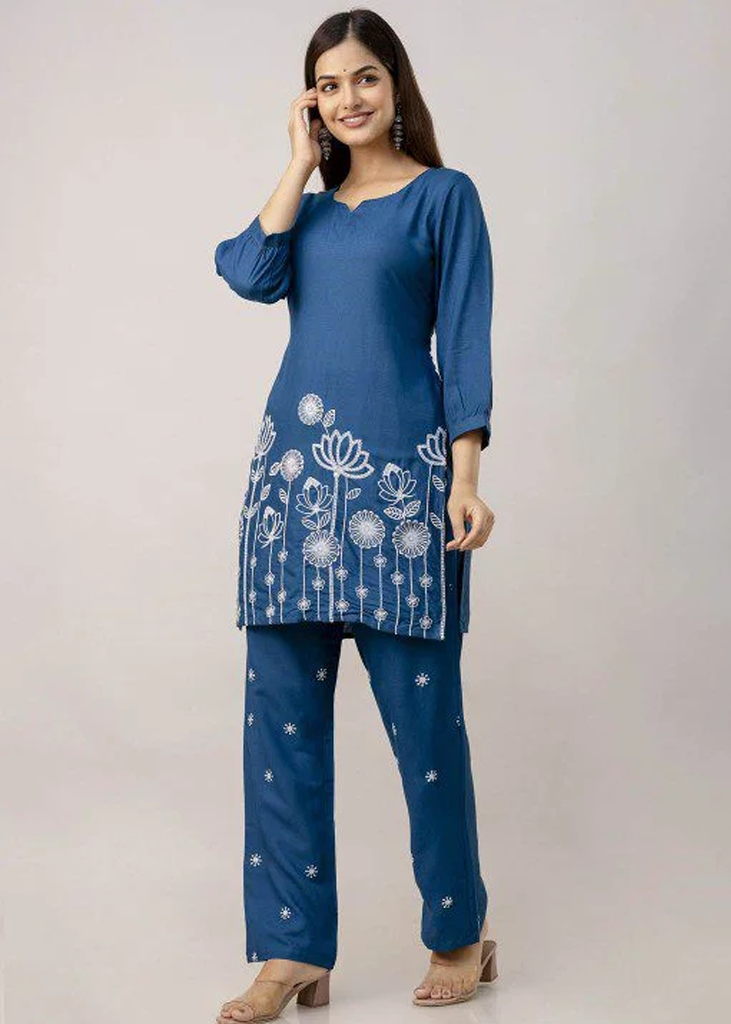 Women’s blue solid straight-fit kurta and pant set in viscose rayon, featuring floral embroidery on the front, a round neckline, three-quarter sleeves, above-knee length, paired with matching embroidered slip-on trousers with an elasticated waistband.
