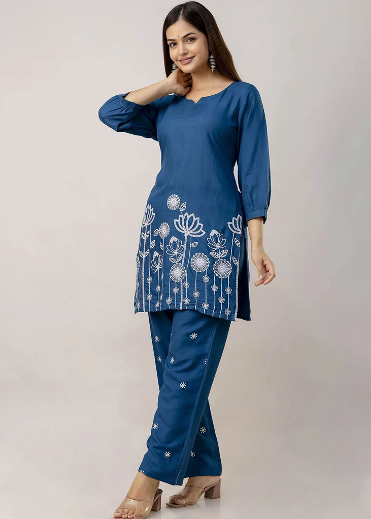 Women’s blue solid straight-fit kurta and pant set in viscose rayon, featuring floral embroidery on the front, a round neckline, three-quarter sleeves, above-knee length, paired with matching embroidered slip-on trousers with an elasticated waistband.