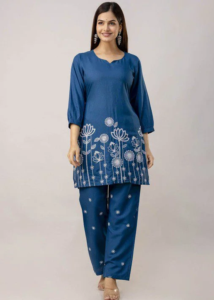Women’s blue solid straight-fit kurta and pant set in viscose rayon, featuring floral embroidery on the front, a round neckline, three-quarter sleeves, above-knee length, paired with matching embroidered slip-on trousers with an elasticated waistband.