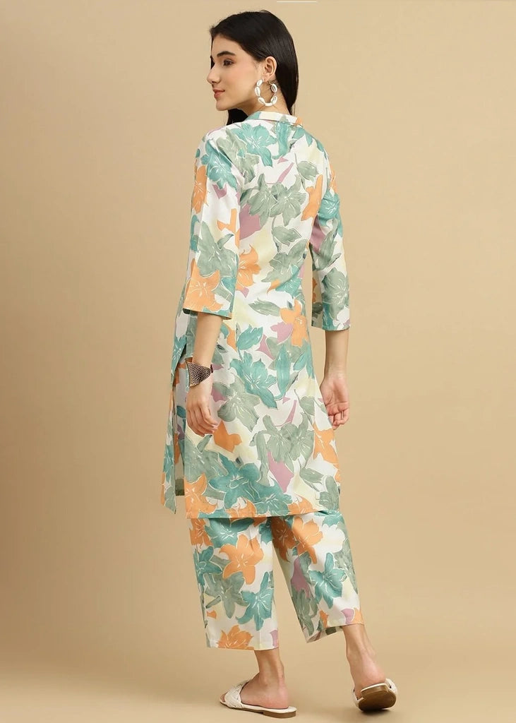 Woman wearing a pink cotton‑rayon floral print kurta and matching straight pants; kurta features a round neckline, three‑quarter sleeves, calf‑length hem, and a flowy a‑line silhouette with side slits.