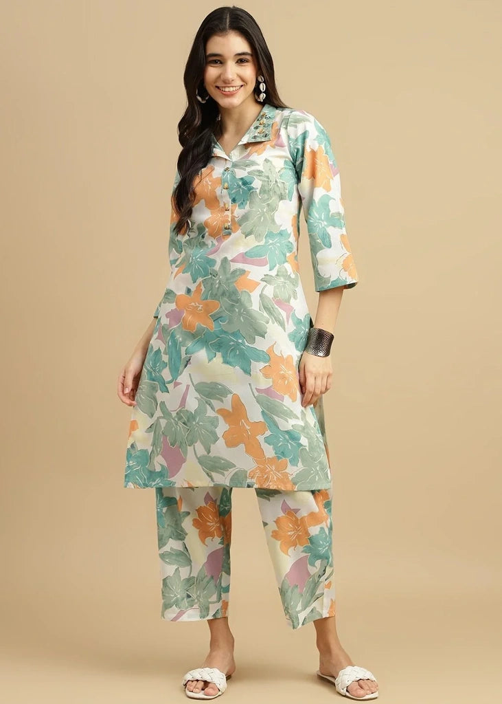 Woman wearing a pink cotton‑rayon floral print kurta and matching straight pants; kurta features a round neckline, three‑quarter sleeves, calf‑length hem, and a flowy a‑line silhouette with side slits.