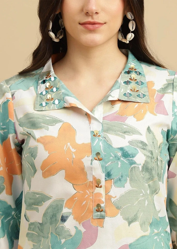 Woman wearing a pink cotton‑rayon floral print kurta and matching straight pants; kurta features a round neckline, three‑quarter sleeves, calf‑length hem, and a flowy a‑line silhouette with side slits.