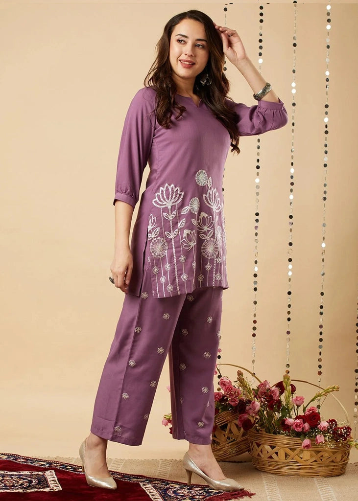 Women's lavender kurta-and-pant set in lightweight fabric, featuring intricate white floral embroidery across the front, with a round neckline, three-quarter sleeves, straight pants, and a streamlined, elegant silhouette.