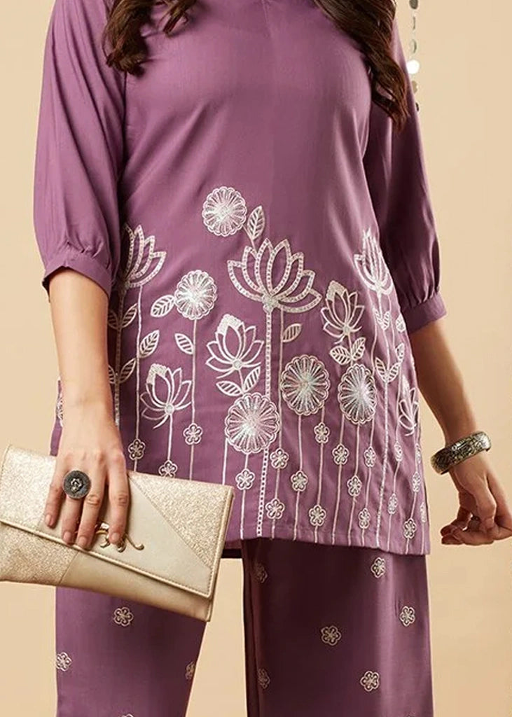 Women's lavender kurta-and-pant set in lightweight fabric, featuring intricate white floral embroidery across the front, with a round neckline, three-quarter sleeves, straight pants, and a streamlined, elegant silhouette.
